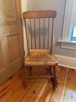 Front view showing spindle backrest and wooden seat with scratches.