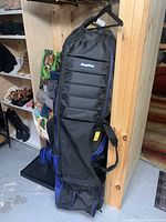 Full view of the Bag Boy travel golf case standing upright showing its black padded front panel with blue edging and handle.