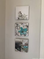 Front view of the three 8x8 inch canvas prints showing stones, flowers, and candle images arranged vertically on a wall.