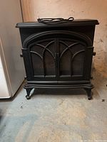 Front view of electric fireplace stove with doors closed showing black metal frame and mesh door design