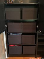 Seven dark grey fabric storage baskets arranged on black shelving unit, showing their uniform size and color.
