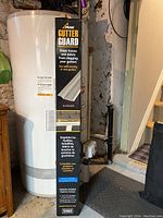 Photo of boxed Peak Gutter Guard showing product details and usage description on packaging, resting near a water heater.