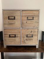 Front view of small wooden mini cabinet showing four drawers with metal label holder handles.