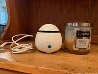 Mini white essential oil diffuser with USB cable and Tuscany Ocean View soy candle on wooden shelf