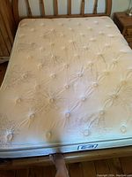 Top view of the queen size mattress showing the light beige quilted pillow top surface with button tufting and decorative stitched patterns.