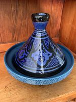 Moroccan tagine pot with lid showing detailed conical lid pattern in blue and black.