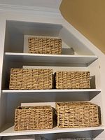 Photo showing all five rectangular wicker baskets stacked on shelves, with 2 larger baskets and 3 smaller baskets arranged.