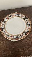 Front view of antique ceramic serving plate with floral and geometric decorative border