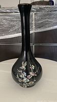 Front view of black ceramic vase with detailed abalone shell inlay floral design