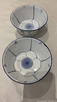 Two blue and white Chinese porcelain rice bowls with flower and spiral patterns seen from above.