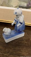 Side view of vintage hand painted Zsolnay porcelain figurine showing girl in bonnet and dress with duck on rectangular base.