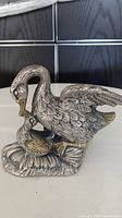 Front view of the vintage silver and gold plated metal mother goose and gosling figure showing the detailed feather textures and gold accents on beaks.