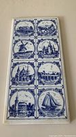 Photo showing 4 blue and white ceramic tiles with Dutch landmarks including windmill, traditional buildings and canals