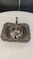 Top angled view of the silver-plated maple syrup dish showing ornate edges and hinged lid with handle.