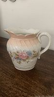 Full view of vintage white ceramic pitcher with floral design and handle