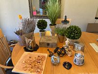 Full lot table view showing assorted decorative items including plants, keys, wooden box, orbs, and figurines arranged on wooden table.
