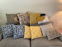 Overview of assorted throw pillows showing various colors and patterns including blue, yellow, beige, and a Colorado map design
