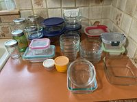 Overview of assorted glass and plastic food storage containers with various lids on kitchen counter