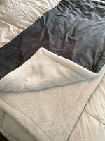 Gray and white plush heated weighted blanket showing the soft gray top side and white Sherpa-style plush bottom side.