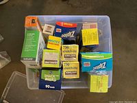 Clear top view of assorted kitchen supplies including multiple sealed boxes of Ziplock bags, Kirkland Stretch-Tite plastic wrap, wax paper, parchment paper, snack and sandwich bags in a plastic container.