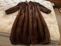 Full front view of brown fur coat laid flat on mattress