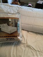 Two queen size mattress covers, one sealed in original Ultra Bensack packaging, other cover laid out showing some stains.