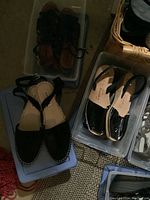 Black women's sandals and glossy black wedge sandals in clear bins.