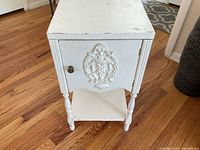 Front view showing decorative raised panel on drawer and turned legs.