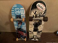 Photo showing the top view of two skateboards with graphics and trucks.