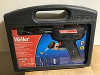 Black Weller soldering gun in carrying case with visible accessories and soldering tips shown inside case.