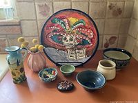 Overview of all items including decorative plate, vase, bowls, oil pitcher, and painted rock arranged on countertop