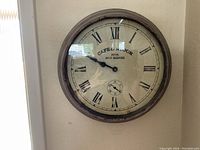Front view of round wall clock showing face, Roman numerals, clock hands, and French text.