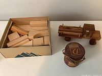 Overview photo showing all items: wooden blocks in an open cardboard box, wooden truck, and paper box