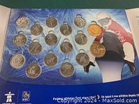Display of 17 coins in blue holder showing a snowboarder in Canada jacket with some coins in clear cases