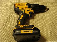 DeWalt cordless hammer drill side view showing battery attached and drill body with brand and voltage labels