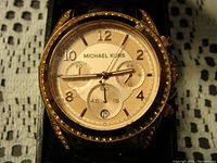 Close up of the watch face showing the rose gold dial, rhinestone bezel, and chronograph subdials.