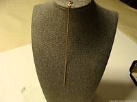 Front view of the entire gold box link bracelet displayed on a gray bust stand showing its length and thin design.