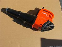ECHO cordless leaf blower with visible orange housing and black blower tube laid out on cardboard.