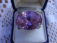 Close image of ring showing oval pink faceted stone in silver setting.