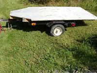 Side view of the yard trailer showing plywood top, tires, and side light.