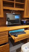 Acer monitor on wooden desk shelf with keyboard and mouse on slide-out drawer.