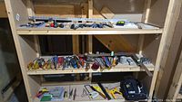 Full view of shelf showing variety of hand tools including screwdrivers, pliers, wrenches, hammers and tool belt on bottom shelf.