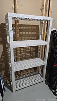 Full view of white PVC shelving unit showing 4 slatted shelves and overall condition.