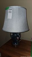 Full view of ceramic table lamp with blue floral patterned base and white fabric shade.