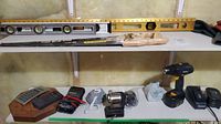 Shelf with cordless drill, chargers, levels, hand tools, calculator, and other miscellaneous items