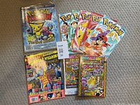 Overview of several Pokémon comic books, guide book, and magazine laid flat on carpet.