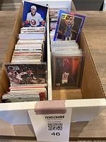 Box of assorted basketball and hockey cards showing multiple stacks and protective sleeves
