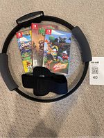 Photo showing Ring Fit Adventure game case along with Ring-Con accessory and leg strap, and two other game cases.