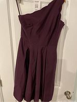 Full view of the purple dress hanging showing pleated skirt and off shoulder design