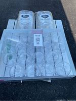 Top and front view of 40 transparent plastic wine cups arranged in a white tray with two unopened packages of wine cups on top.